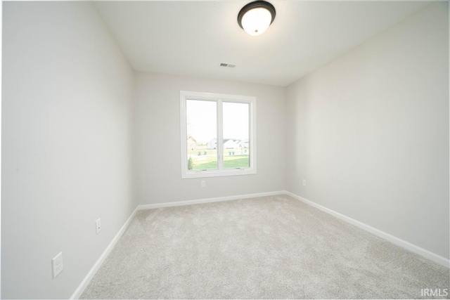 empty room with baseboards, visible vents, and light colored carpet