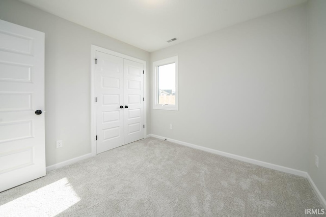 unfurnished bedroom with light carpet, baseboards, and a closet