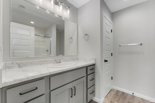 bathroom featuring visible vents, a stall shower, vanity, wood finished floors, and baseboards