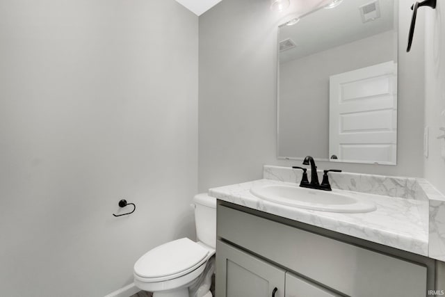 bathroom featuring toilet, vanity, visible vents, and baseboards