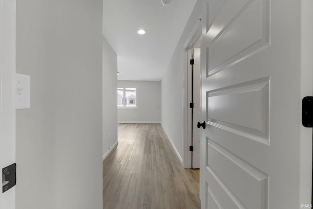 corridor with light wood-type flooring and baseboards