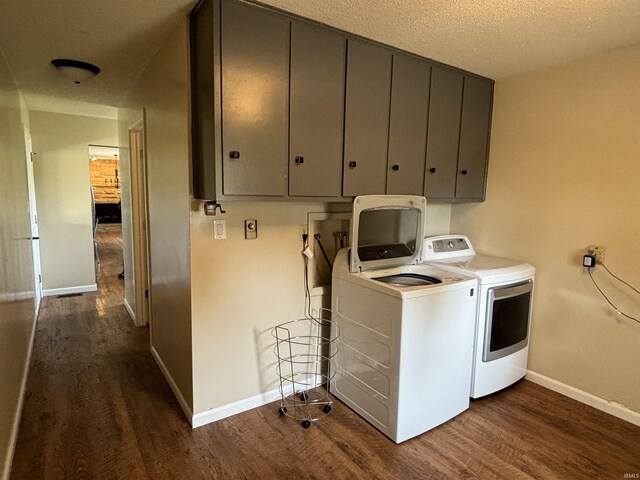 clothes washing area featuring washer and dryer, cabinets, a textured ceiling, and dark wood-type flooring