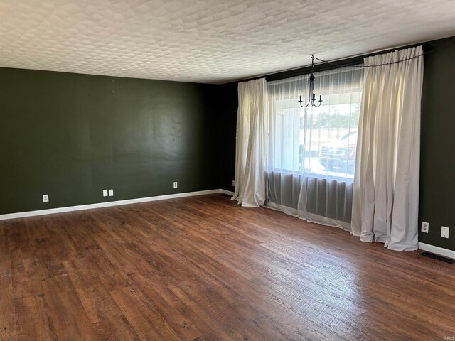 empty room featuring dark wood-type flooring and a textured ceiling