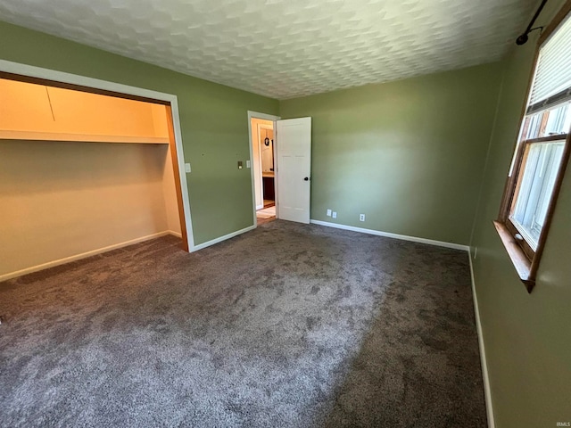 unfurnished bedroom with dark carpet, a closet, and a textured ceiling