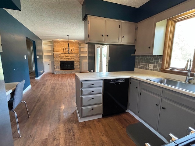 kitchen featuring a fireplace, black dishwasher, kitchen peninsula, and dark wood-type flooring