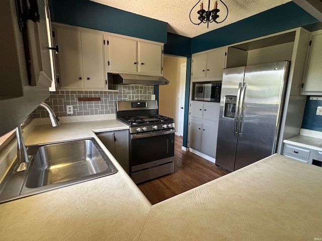 kitchen featuring a textured ceiling, backsplash, dark hardwood / wood-style flooring, sink, and appliances with stainless steel finishes