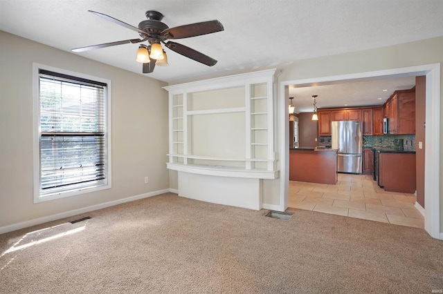 unfurnished living room with ceiling fan, light colored carpet, and a textured ceiling