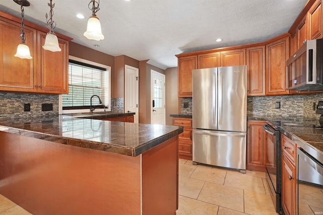 kitchen with pendant lighting, appliances with stainless steel finishes, sink, decorative backsplash, and light tile patterned flooring