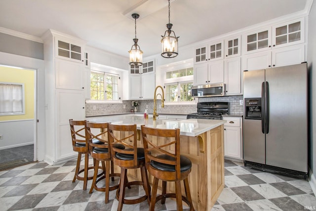 kitchen featuring an island with sink, pendant lighting, appliances with stainless steel finishes, and white cabinets