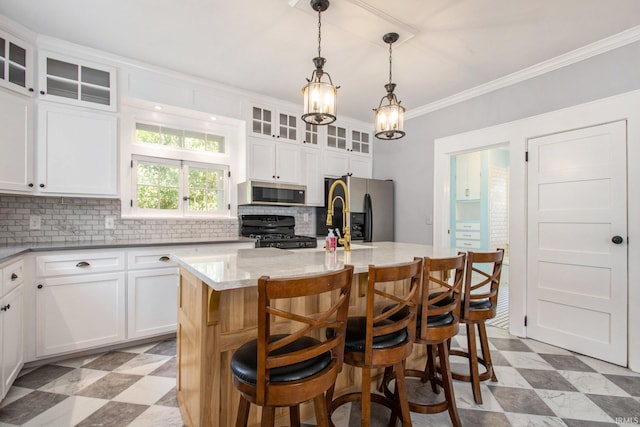 kitchen featuring appliances with stainless steel finishes, an island with sink, and white cabinetry