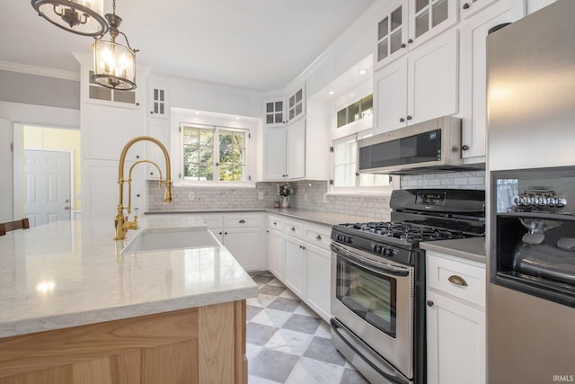 kitchen with white cabinetry, a chandelier, an island with sink, light stone countertops, and appliances with stainless steel finishes