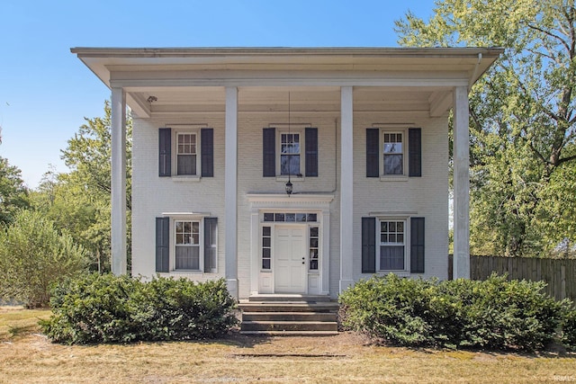 greek revival inspired property featuring brick siding and fence