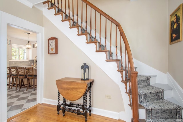 stairway with wood-type flooring and a chandelier