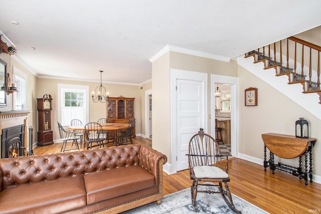 living room with light wood-type flooring, ornamental molding, and a chandelier