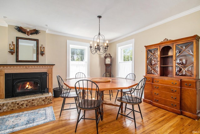 dining area featuring ornamental molding, a healthy amount of sunlight, an inviting chandelier, and light hardwood / wood-style floors