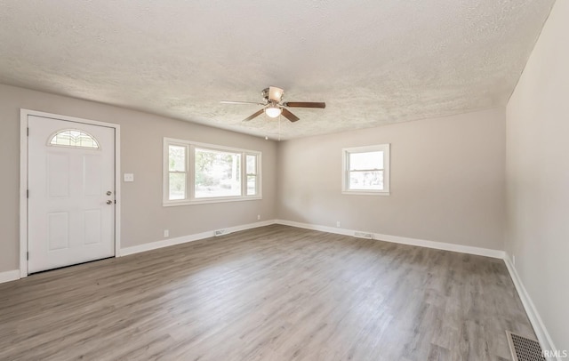 foyer entrance with a textured ceiling, a healthy amount of sunlight, ceiling fan, and light hardwood / wood-style floors