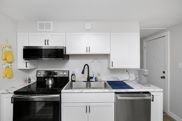 kitchen featuring a textured ceiling, stainless steel appliances, sink, and white cabinets