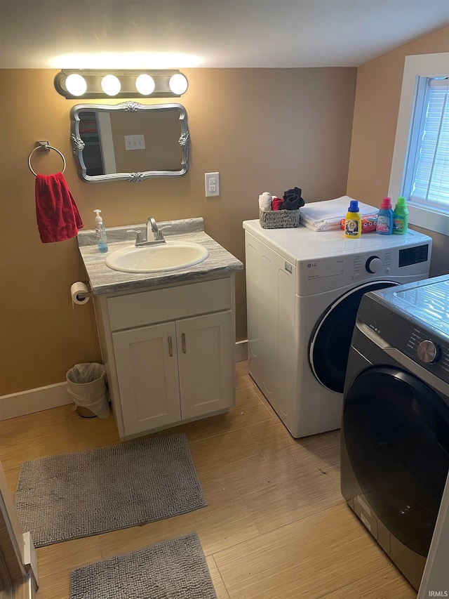 washroom with light wood-type flooring, independent washer and dryer, and sink