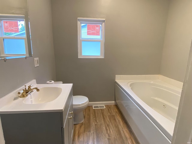 full bathroom featuring a garden tub, visible vents, toilet, vanity, and wood finished floors