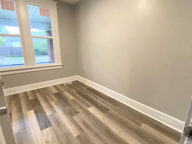 spare room featuring visible vents, baseboards, and wood finished floors