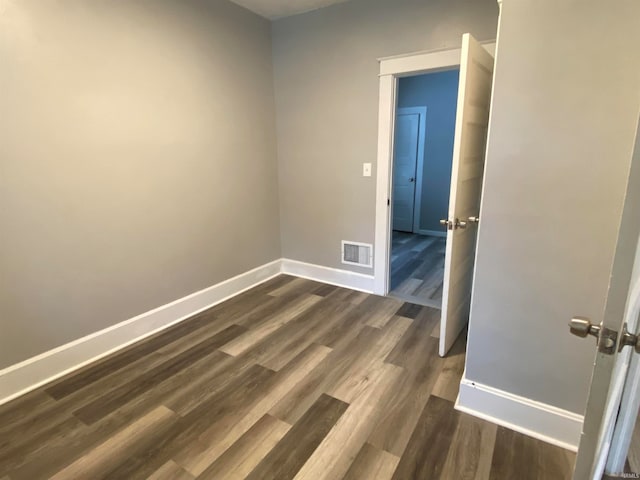 unfurnished room featuring dark wood-style floors, visible vents, and baseboards