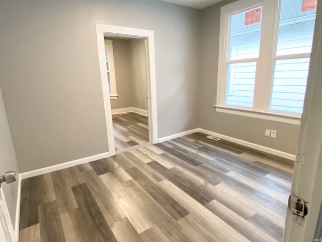 spare room featuring dark wood-style floors, visible vents, and baseboards