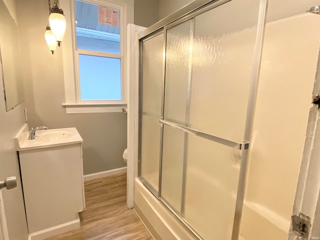 full bath featuring baseboards, toilet, wood finished floors, combined bath / shower with glass door, and vanity