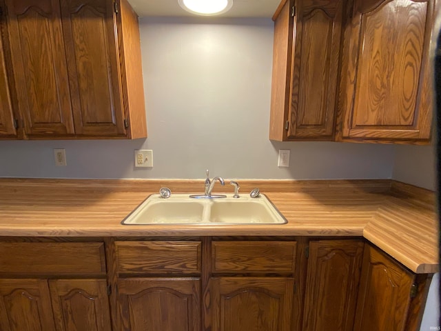 kitchen featuring brown cabinets, light countertops, and a sink