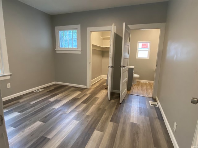 interior space with dark wood-style floors, a spacious closet, visible vents, and baseboards