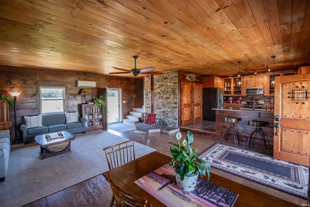 interior space with a wall unit AC, hardwood / wood-style flooring, wooden ceiling, wood walls, and ceiling fan