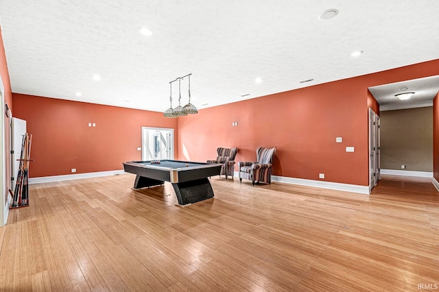 game room featuring light wood-type flooring, pool table, and a textured ceiling