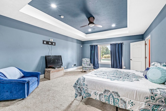 carpeted bedroom with a raised ceiling and ceiling fan