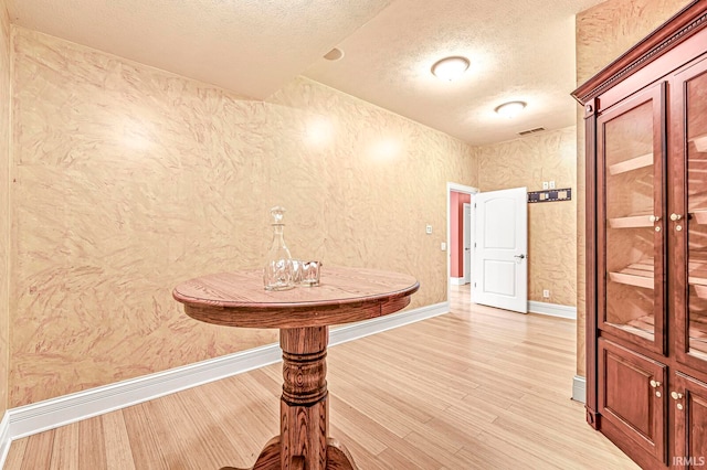 corridor featuring light wood-type flooring and a textured ceiling