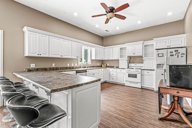 kitchen with white gas stove, white cabinetry, kitchen peninsula, and ceiling fan