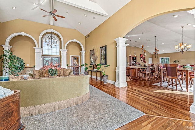 living room featuring ceiling fan with notable chandelier, hardwood / wood-style flooring, ornate columns, and a wealth of natural light