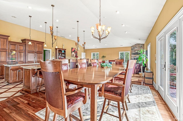 dining space featuring a healthy amount of sunlight, hardwood / wood-style floors, a notable chandelier, and vaulted ceiling