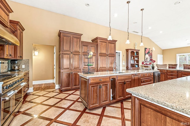 kitchen with range with two ovens, decorative light fixtures, an island with sink, sink, and lofted ceiling