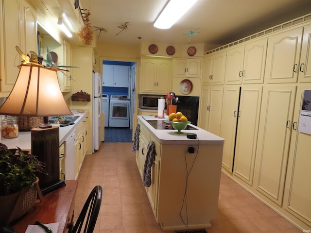 kitchen featuring light tile patterned floors, a center island, black oven, and independent washer and dryer