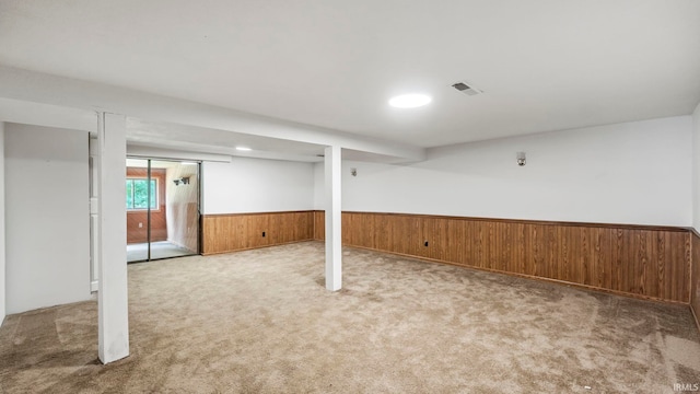 basement featuring wooden walls and light carpet