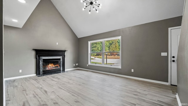 unfurnished living room featuring a high end fireplace, light wood-type flooring, high vaulted ceiling, and a notable chandelier