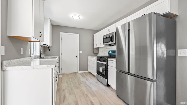 kitchen with stainless steel appliances, light hardwood / wood-style floors, white cabinetry, and sink