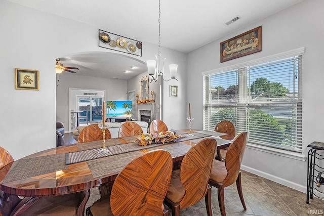 dining area with ceiling fan with notable chandelier and tile patterned flooring