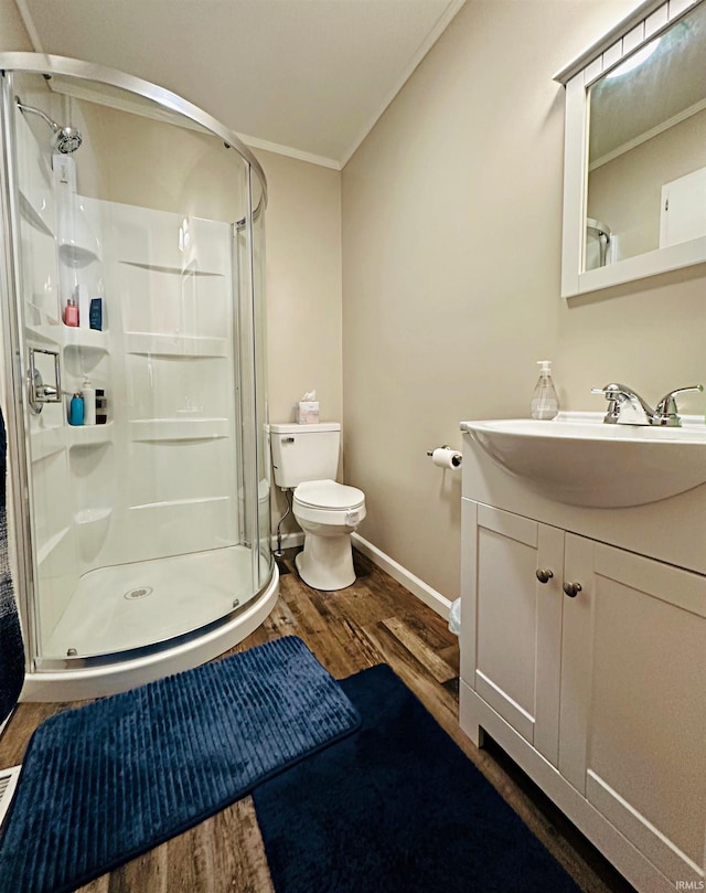 bathroom with toilet, ornamental molding, vanity, wood-type flooring, and a shower with shower door