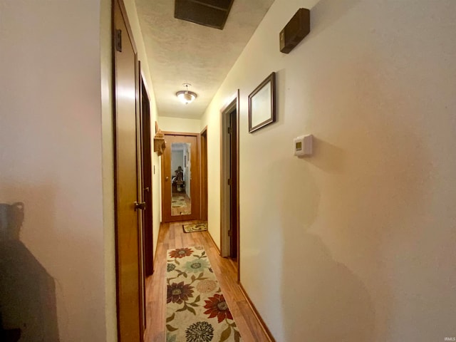 hall featuring a textured ceiling and light hardwood / wood-style floors