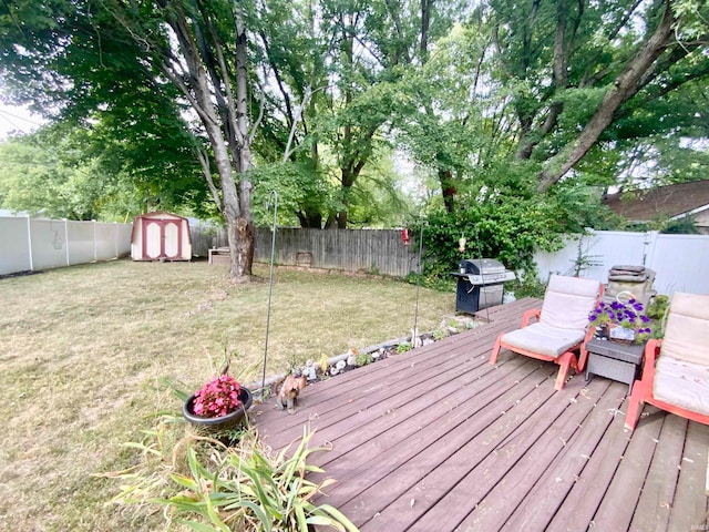 wooden terrace featuring a storage shed, a yard, and grilling area