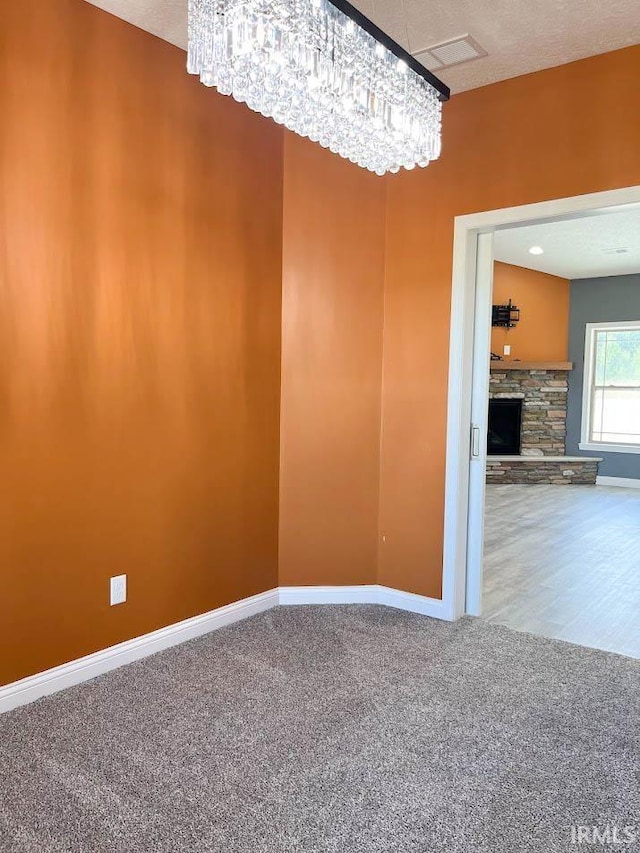 unfurnished room featuring carpet flooring, a fireplace, and a textured ceiling