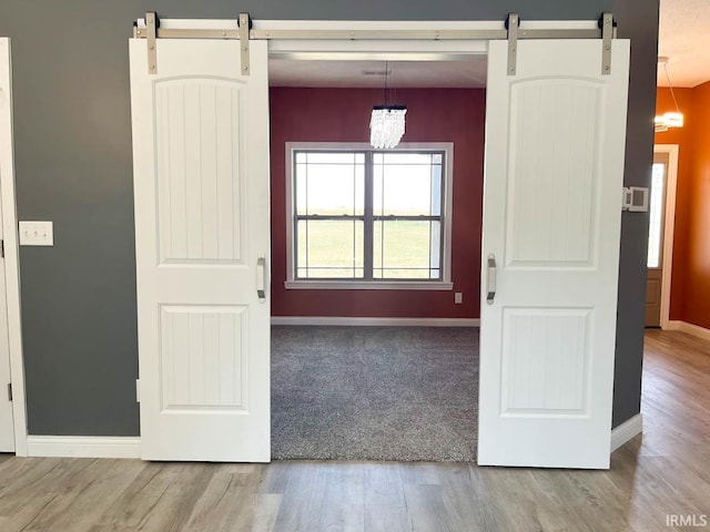 interior space featuring a barn door, an inviting chandelier, and light hardwood / wood-style flooring