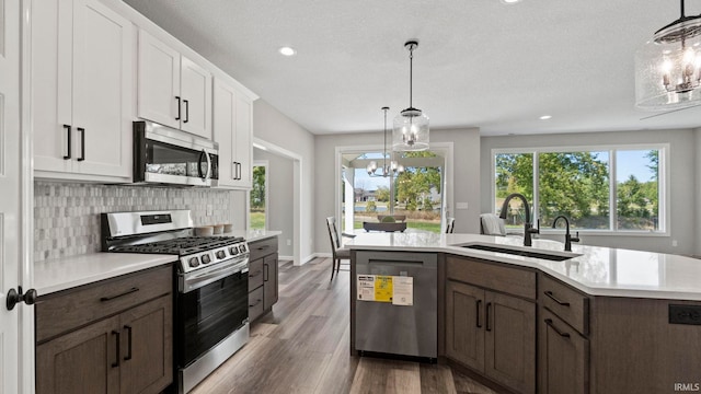 kitchen with white cabinets, decorative light fixtures, stainless steel appliances, a chandelier, and dark hardwood / wood-style floors