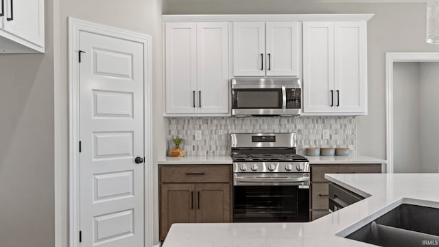 kitchen with appliances with stainless steel finishes, white cabinets, and decorative backsplash