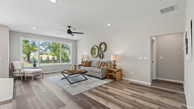 living room with a textured ceiling, hardwood / wood-style flooring, and ceiling fan